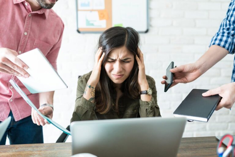 Overwhelmed office worker stressed from task overload – a scenario digital signage in Singapore can help reduce with clearer internal communication.